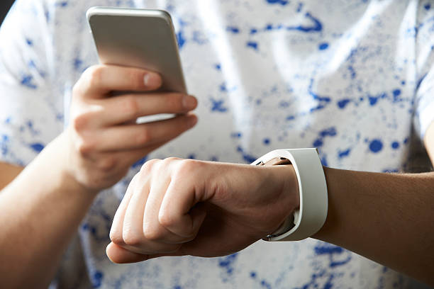istock Young Man Synchronizing Smart Watch With Mobile Phone 511995510
