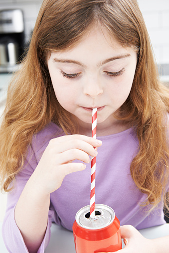 Young Girl Drinking Can Of Soda Through Straw
