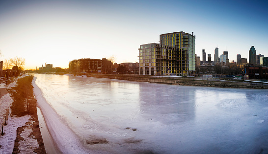 Frozen canal Lachine River at sunset panorama with condo buildings under construction and downtown Montreal in the background.