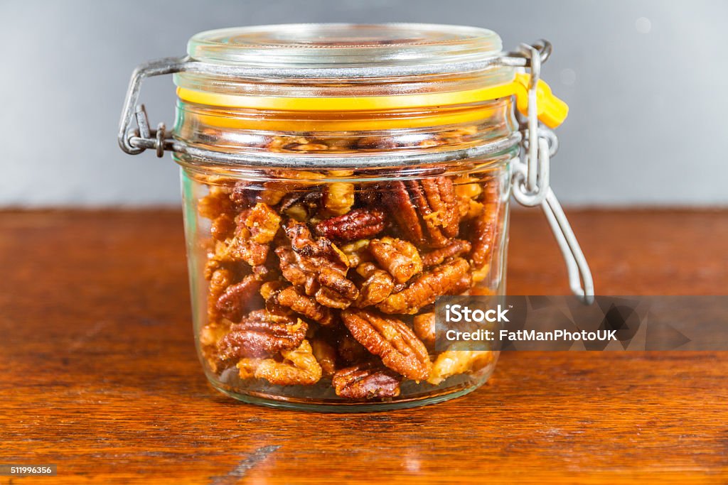 Jar with mixed garlic and rosemary roasted nuts. Pecan nuts and walnuts roasted with garlic and rosemary in jar. Dark background. Bar - Drink Establishment Stock Photo