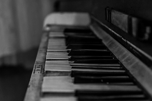 Old, rugged piano. Black and white, low light photography.