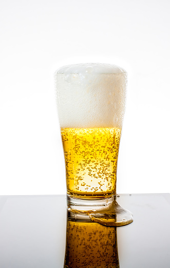 Glass of fresh beer with cap of foam isolated on white background