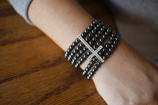 A woman's arm with a beaded cross bracelet.