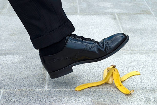 Businessman stepping on banana skin stock photo