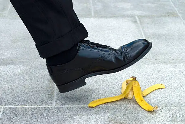 Photo of Businessman stepping on banana skin