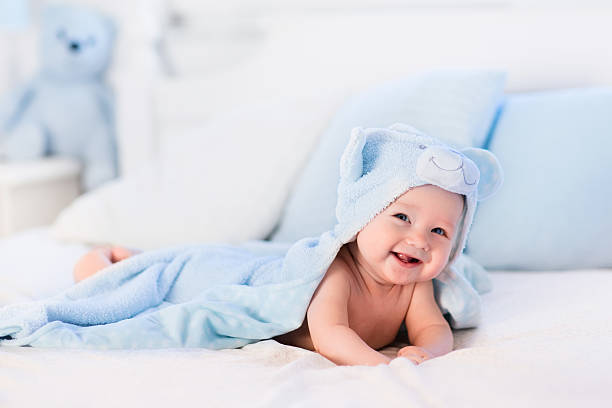 istock Baby boy in blue towel on white bed 512002022