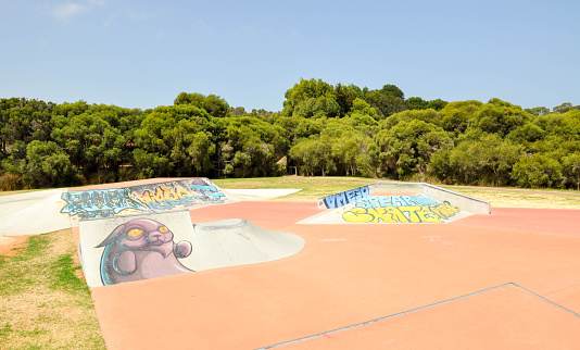 Spearwood,WA,Australia-January 5,2016: Concrete banked ramps with urban art at Spearwood Skate Park in treed setting in Spearwood, Western Australia.