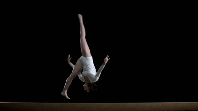 SLO MO Female gymnast doing a flip on balance beam