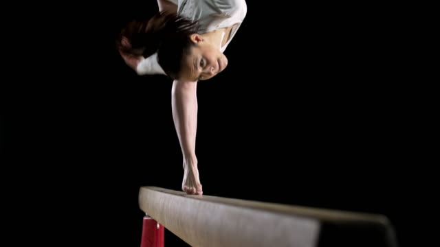 SLO MO Female gymnast performing a flip on balance beam