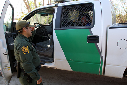 Rio Grande City, Texas, USA - February 9, 2016:  A Border Patrol agent takes a Mexican man into custody for illegally entering the U.S. by crossing the Rio Grande River in the Rio Grande Valley in far south Texas.  A continuous game of cat and mouse plays out along the river twenty four hours a day.