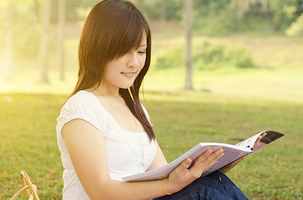 istock Young Asian college girl student reading book 512038778