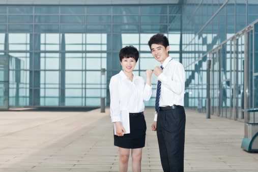 asian businessman and businesswoman standing face to face, making a fist.
