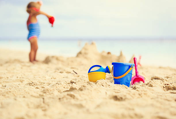 kinder spielzeug und kleine mädchen gebäude sandburg - lifestyles child beach digging stock-fotos und bilder