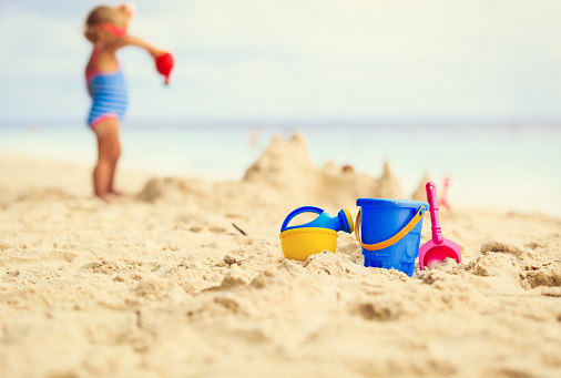 kids toys and little girl building sandcastle, family vacation