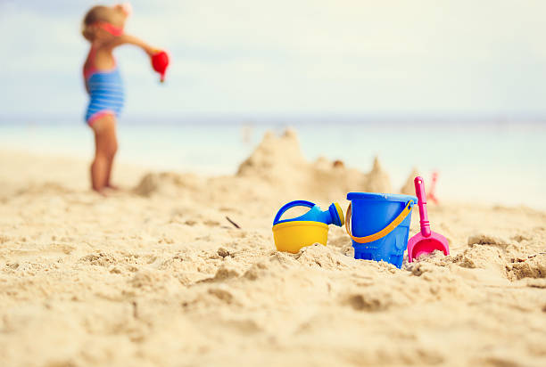 дет�ские игрушки и маленькая девочка здание сандкасл - lifestyles child beach digging стоковые фото и изображения