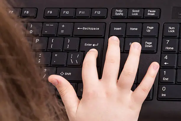 Finger female hand presses the Enter-key on a black keyboard closeup