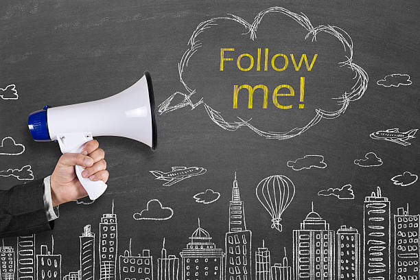 istock Hand holding megaphone with Follow me on cityscape background 512041100