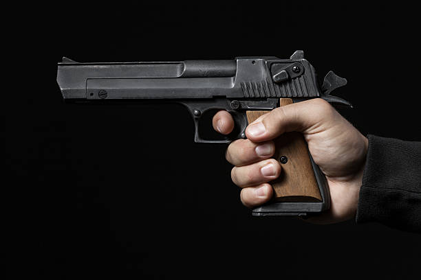 istock male hand with gun isolated on black background 512041387