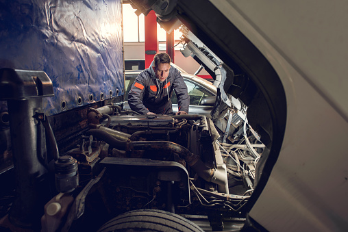 Auto mechanic working on a truck in a repair shop.