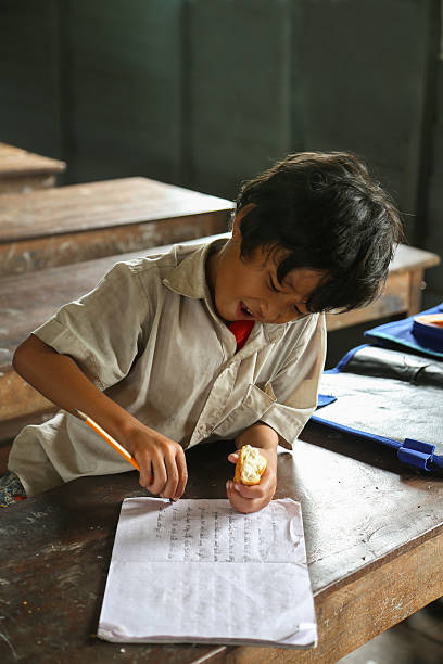 Cambodian kid in the classroom writing in ht enotebook