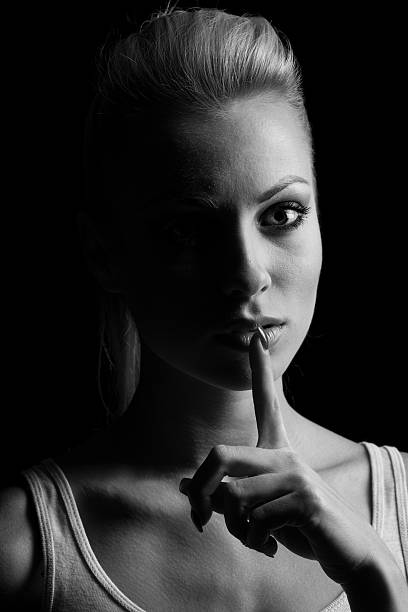 istock Mystery woman in shadow with finger on lips gesturing silence. 512046644