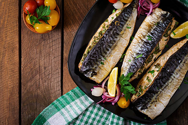 Baked mackerel with herbs and garnished with lemon Baked mackerel with herbs and garnished with lemon and pickled vegetables. Top view mackerel stock pictures, royalty-free photos & images