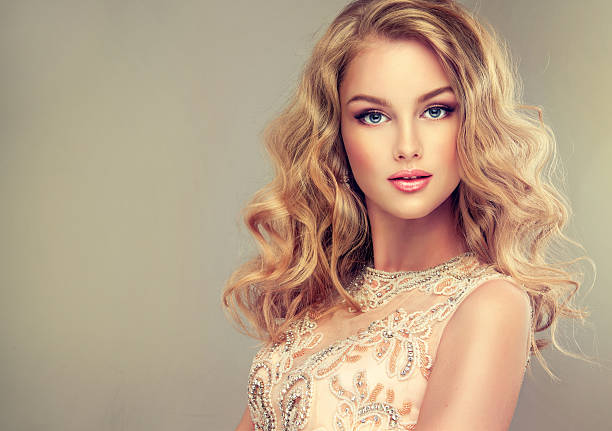Young beautiful woman, dressed in evening gown. Young beautiful woman, dressed in evening gown. Loose,wavy hair and bright make up. Straight look on camera. blonde model in dress stock pictures, royalty-free photos & images