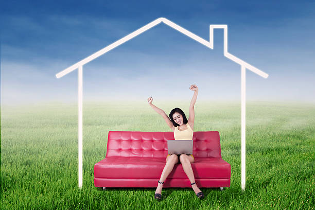istock Girl with laptop on sofa under a dream house 512052958