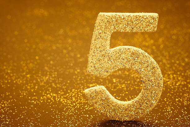 istock Number five golden color over a warm background. Anniversary 512054708