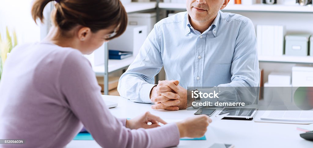 Business meeting Mature businessman and young woman having a business meeting in the office, they are discussing together Advice Stock Photo