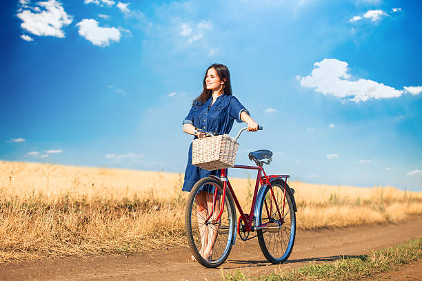 istock Brunette girl  with bycicle on countryside road. 512058983