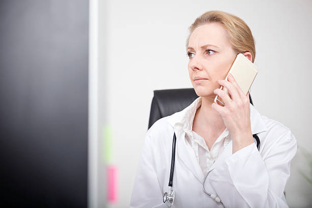 woman doctor calling on mobile and looking to left - nurse on phone serious bildbanksfoton och bilder