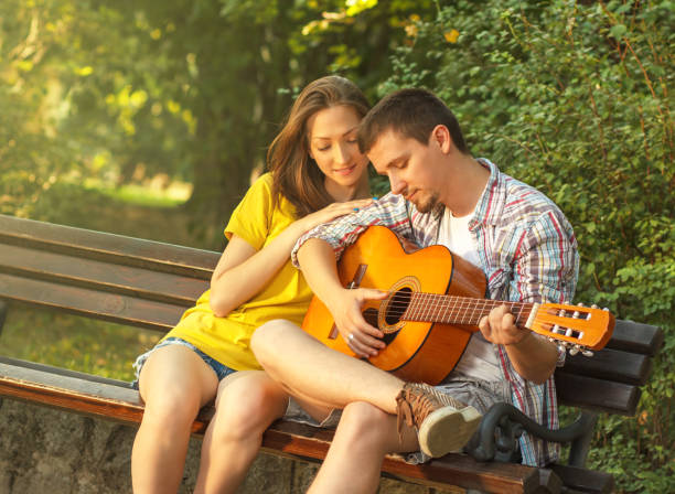 istock Young couple playing guitar at the park 512082889