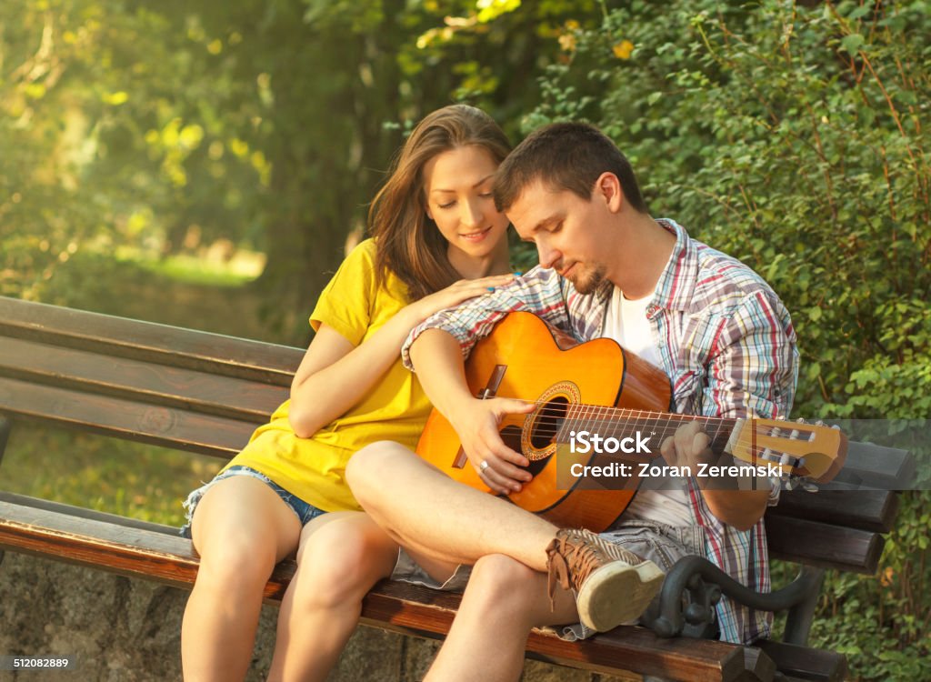 Young couple playing guitar at the park Young couple in love playing acoustic guitar in the park 20-24 Years Stock Photo