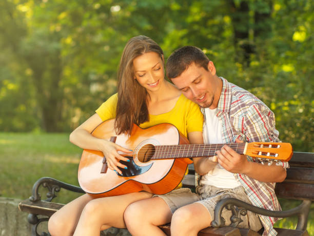 istock Young couple playing guitar at the park 512082901