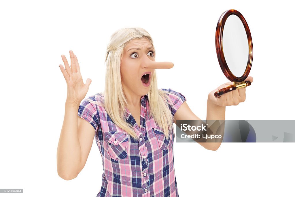 Shocked woman looking at her long nose in a mirror Shocked woman looking at her long nose in a mirror isolated on white background 20-29 Years Stock Photo