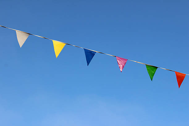 istock Row of rainbow coloured bunting flags on rope, against blue-sky 512086453