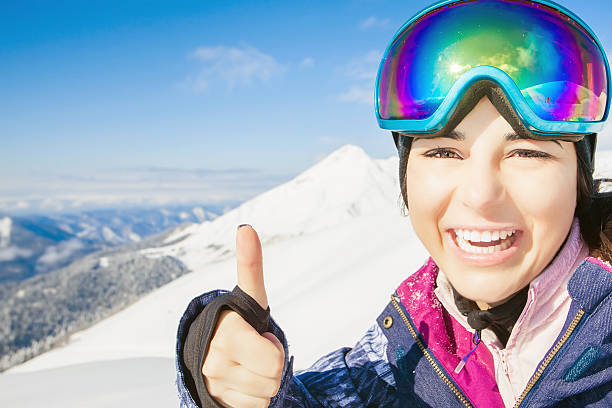 Happy girl dressed in ski or snowboard fashion mask goggles Happy girl dressed in ski or snowboard fashion mask goggles. Successful gesture thumbs up. Mountain landscape. Extreme adventure. Winter ski resort thumbs up for skiing stock pictures, royalty-free photos & images