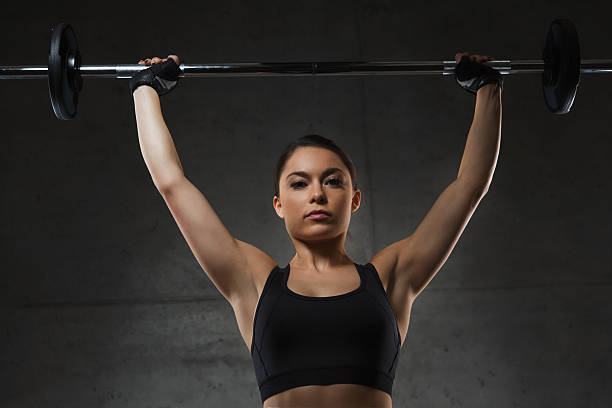 istock young woman flexing muscles with barbell in gym 512095060