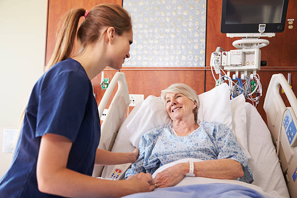 Nurse Talking To Senior Female Patient In Hospital Bed Nurse Talking To Senior Female Patient In Hospital Bed hospital patient bed nurse stock pictures, royalty-free photos & images