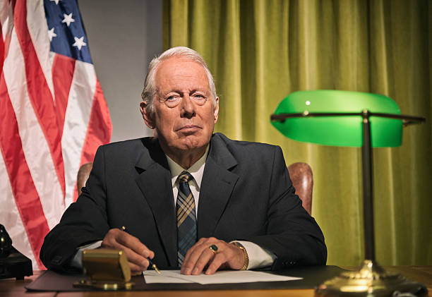 istock Big boss president writing behind desk with american flag. 512099149