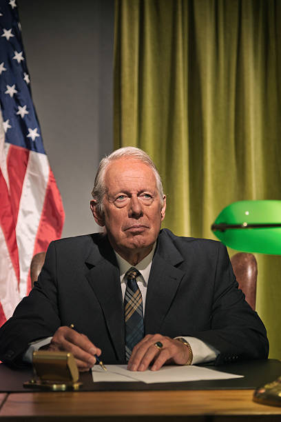 istock Big boss president writing behind desk with american flag. 512099153