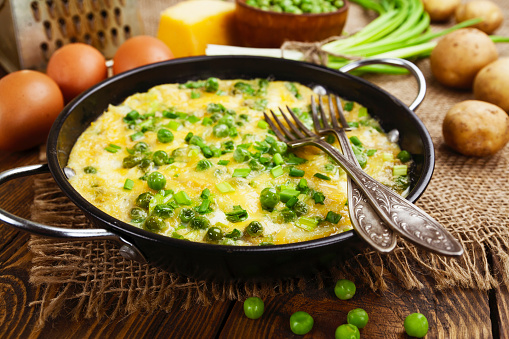 Scrambled eggs with green peas, potatoes and cheese