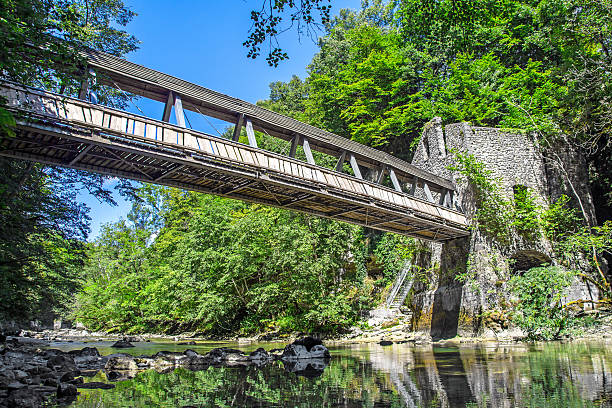 istock Pedestrian bridge crossing wild river with old mill building 512100680