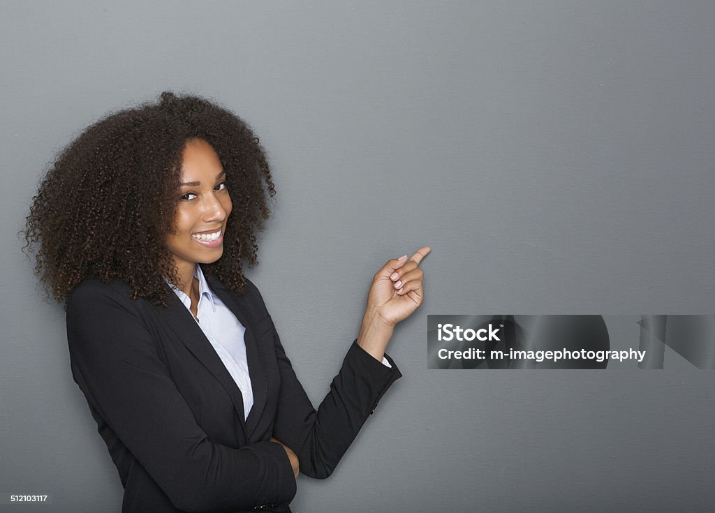 Friendly business woman pointing finger Close up portrait of a friendly business woman pointing finger on gray background Pointing Stock Photo