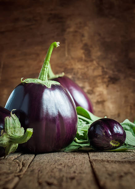 istock Dark Round Eggplants on the wooden background 512106303