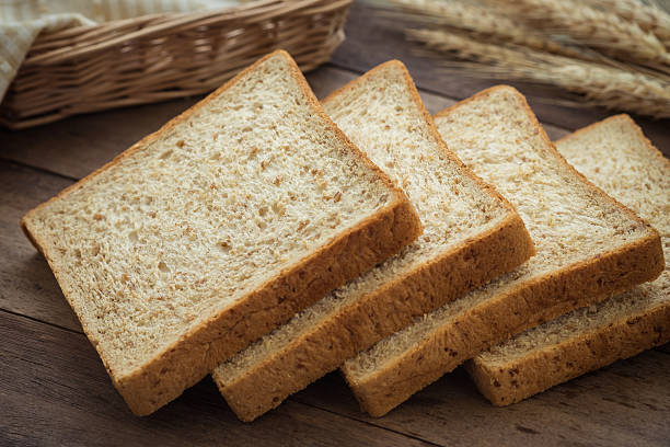 istock Whole wheat bread slices and wheat on wooden table 512106452