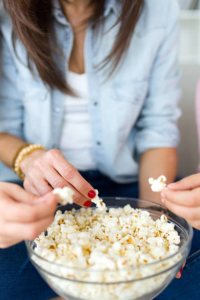 istock Beautiful mother and her daughters eating popcorns at home. 512106936