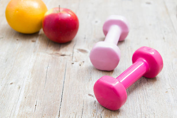 istock Dumbbell weights and fruit orange and apple health concept 512112524