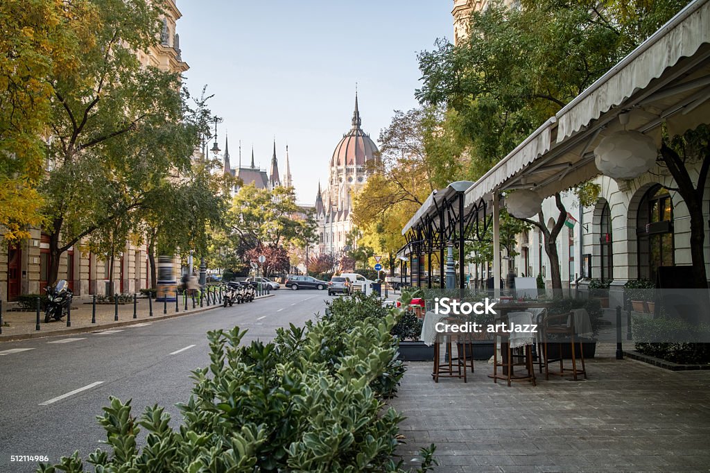 Street of Budapest with view at the Hungarian Parliament Street of Budapest with a pavement cafe and a view at the Hungarian Parliament Building on a bright autumn day Budapest Stock Photo